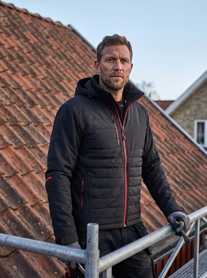 Dachdecker in der Hybridjacke auf dem Gerüst
