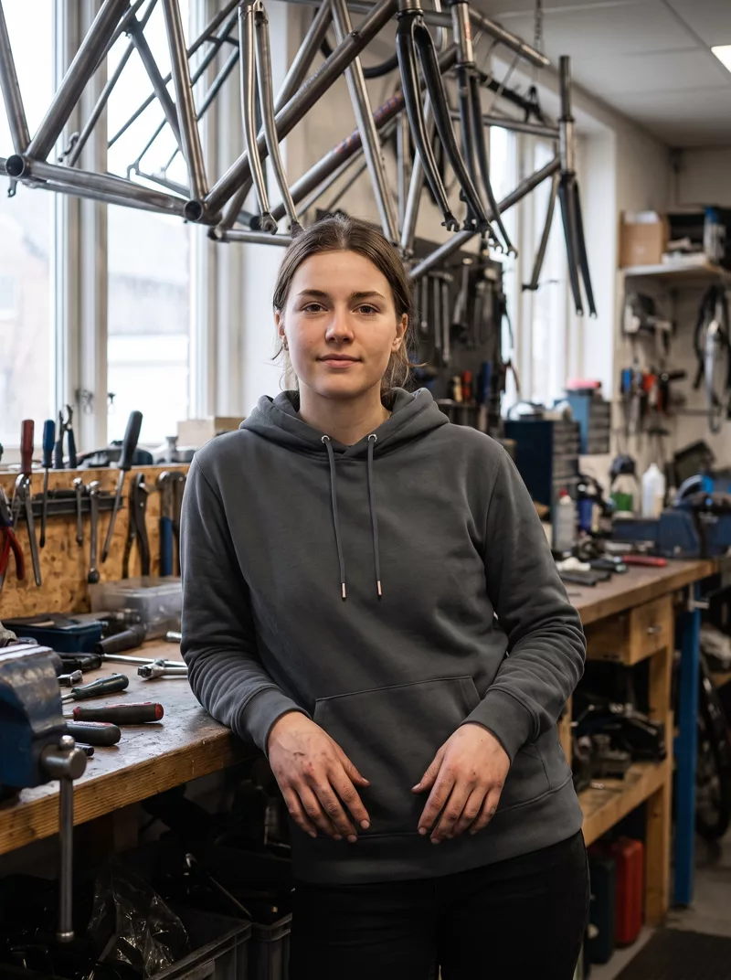 Mitarbeiterin im Cruiser-Hoodie in einer Fahrradwerkstatt